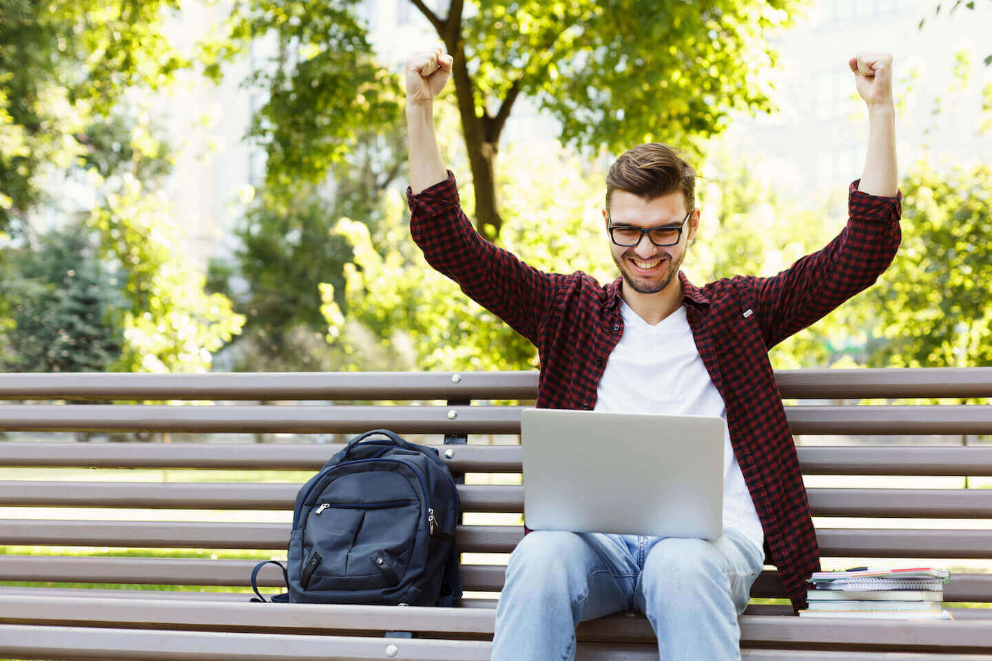 Male student on laptop celebrating winning a scholarship